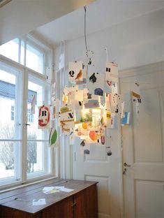 a chandelier hanging from the ceiling in front of a window filled with pictures