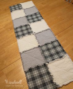 a table runner made out of plaid fabric on top of a wooden floor with chairs in the background