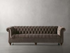 a couch sitting on top of a gray floor next to a white wall in an empty room