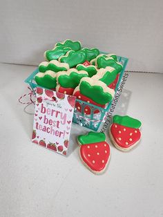 a box filled with lots of decorated cookies next to a bag of strawberries and strawberry shortbreads