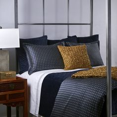 a bed with black and gold comforters in a bedroom next to a night stand