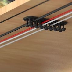 two black and red wires connected to each other on top of a wooden table next to a painting