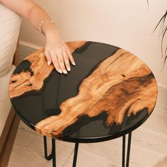 a person's hand resting on top of a black and wood table with metal legs