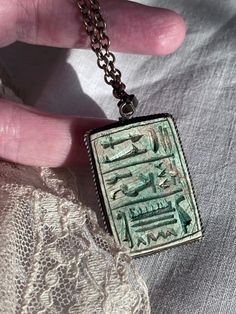 1970s Egyptian Revival Carved Hieroglyphics Ceramic Double Sided Two Tone Pendant Necklace Measurements in inches: Length of pendant 1.5 Width of pendant 1 Length of chain 20 Ceramic double sided carved pendant One side green One side bone color All vintage items have been given estimated ages based on quality, materials, design and features of the pieces. These are estimates and not exact.  All items are in wearable vintage condition, unless otherwise stated. We do our best to show any major issues like rips or discoloration in photos of the item.  Measurements are taken by hand. Collectible Etched Amulet Jewelry, Etched Spiritual Necklaces For Collectors, Vintage Metal Ankh Necklace, Vintage Ankh Metal Necklace, Vintage Ankh Necklace In Metal, Collectible Pendant Necklace With Etched Detail, Vintage Etched Necklaces For Collectors, Antique Engraved Rectangular Pendant Necklace, Antique Engraved Necklace With Rectangular Pendant