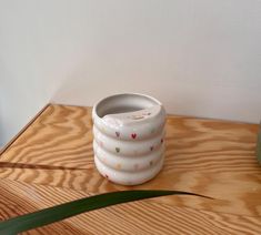 a white vase sitting on top of a wooden table next to a potted plant