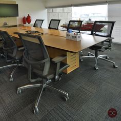 an empty conference room with chairs and a large wooden table in front of a flat screen tv