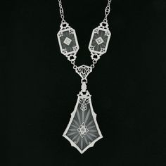 "This is a magnificent antique pendant necklace that was crafted during the art deco period in solid 14k white gold. It features three camphor glass panels with the largest dangling at the center, and each is set with a fine old single cut diamond that adds a lovely touch of sparkle to this piece. The camphor glass displays magnificent etching designs and is elegantly bezel set and framed with etched patterns throughout and further adorned with lovely floral filigree work. The largest camphor gl Luxury Art Deco Necklace With Polished Finish, Victorian White Gold Pendant Necklace, Antique White Gold Necklace With Intricate Design, Antique White Gold Filigree Necklace, Art Deco Diamond Cut Necklace For Anniversary, Antique White Gold Necklace With Filigree, Antique Evening Necklace With Intricate Design, Victorian Evening Necklaces With Intricate Design, Victorian Necklaces With Intricate Design For Evening