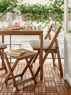 a wooden table with two chairs next to plants