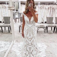 a woman taking a selfie in front of a mirror wearing a white wedding dress