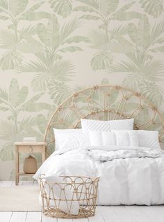 a white bed sitting in a bedroom next to a wallpaper covered with green leaves