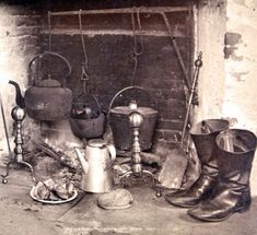 an old fireplace with many pots and pans on the mantle, including one watering can