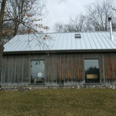 a house with metal roof and windows in the grass