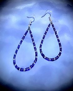 These beautiful 2 3/4" earrings are made with blue and purple and silver seed beads. These beads are a nice embellishment to the classic teardrop hoop earrings. These teardrop earrings are very comfortable because they are so lightweight.  Hoop earrings are classic, and these are teardrop hoops, with a pattern that makes a statement. You can't go wrong with these earrings! They are great all year round. These would be great on to wear on July fourth! They come in a box for easy gift giving too. They are a great birthday, Mother's Day, or Christmas gift! 1006 Dangle Teardrop Earrings With Tiny Beads As Gift, Gift Teardrop Dangle Earrings With Tiny Beads, Purple Teardrop Jewelry With Dangling Beads, Blue Dangle Hoop Earrings With Tiny Beads, Purple Teardrop Beaded Earrings With Dangling Beads, Purple Teardrop Earrings With Dangling Beads, Blue Beaded Teardrop Earrings For Gift, Purple Beaded Teardrop Earrings With Ear Wire, Purple Beaded Dangle Hoop Earrings