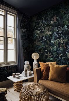 a living room filled with furniture and wallpaper covered in green plants on the walls