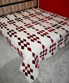 a bed with a white and red quilt on it