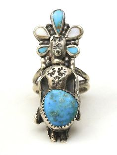 an old silver and turquoise stone ring on a white background with the image of a woman's head