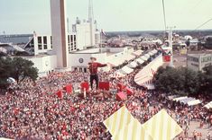 an aerial view of a crowd at a fair with a man standing on the stage