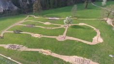 an aerial view of a grassy area with trees, rocks and dirt paths in the middle