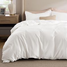 an unmade bed with white sheets and pillows