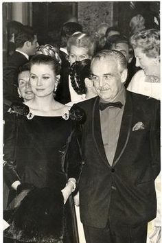 an old black and white photo of two people in formal wear standing next to each other