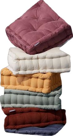 four pillows stacked on top of each other in different colors and sizes, with one folded up