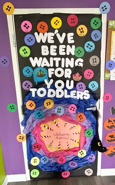 a door decorated with buttons and saying we've been waiting for you to toddlers