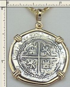 a gold and silver pendant with an image of a cross in the center, on a white background