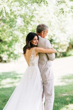 an older man and woman hugging each other in the grass at their outdoor wedding ceremony