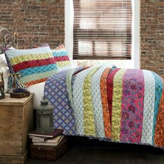 a bedroom with brick walls and a bed covered in multicolored bedspread