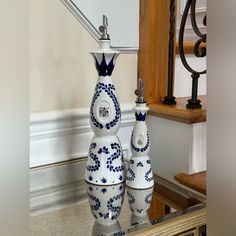 two blue and white vases sitting on top of a glass table next to a stair case