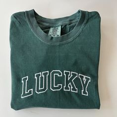 Celebrate St. Patricks Day with the varsity print LUCKY tee!  Please wash on gentle cycle and dry on low.  If you are wanting a different design, wording, or a different clothing style, please send me a message so we can discuss the details. Sporty T-shirt With Embroidered Graphics For Game Day, Collegiate Tops With Embroidered Graphics For College, Collegiate Embroidered Crew Neck T-shirts, Collegiate Cotton T-shirt With Embroidered Graphics, Varsity Tops With Embroidered Graphics For Game Day, Cotton Tops With Embroidered Graphics For Sports Events, Collegiate Tops With Embroidered Graphics For Game Day, Collegiate Long Sleeve T-shirt With Letter Embroidery, Collegiate Crew Neck Top With Embroidered Graphics