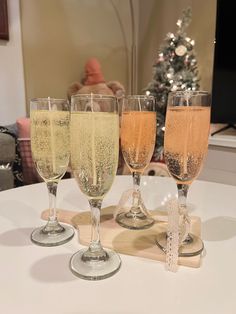 three glasses of champagne on a table with a christmas tree in the backgroud