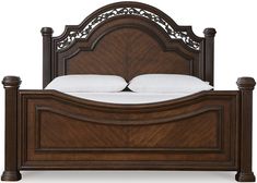 a wooden bed with white pillows on top of it and an ornate headboard above the bed