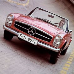 a red convertible car driving down a street