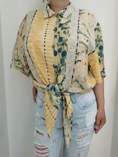 Vintage tie waist button up shirt from the 1990's. Women's short sleeve button up blouse with a tie waist. Beautiful 90's print in tones of yellow, beige, black and green. Oversized fit. Material: Tag has faded. Feels like viscose. Size: Marked 48 DE, which is 18 US or XL. Model on the second photo is 40 DE or L. To be sure this item would fit you, please look at the measurements below. Approximate measurements (taken when shirt is lying flat, double armpit to armpit and waist): Shoulder to shou Summer Tops With Tie Sleeves And Short Sleeve, Summer Short Sleeve Blouse With Tie Sleeves, Casual Summer Blouse With Tie Waist, Summer Blouse With Tie Sleeves And Short Sleeve, Spring Short Sleeve Blouse With Tie Waist, Spring Blouse With Tie Waist And Short Sleeves, Casual Short Sleeve Blouse With Tie Waist, Casual Short Sleeve Blouse With Tie Sleeves, Summer Tops With Tie Sleeves And Relaxed Fit