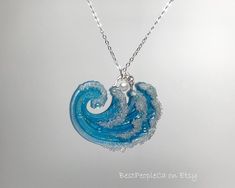 a blue and white wave necklace on a silver chain