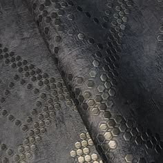 an upholstered black and gold fabric with hexagons on it's surface