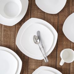 white plates and silverware are laid out on a wooden table