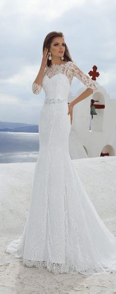 a woman in a white wedding dress standing on the beach with her hands behind her head