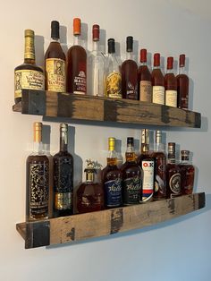 several bottles of liquor are lined up on the wall above a shelf that is made out of wooden planks