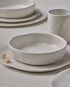 white dishes and cups are arranged on the table top, ready to be used as place settings