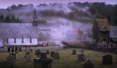 a graveyard with fog in the background and an old church on top is shown at dusk