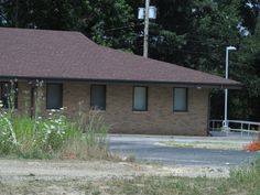 a small brick building sitting next to a forest