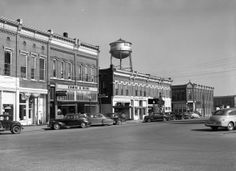 an old black and white photo of cars parked in front of buildings