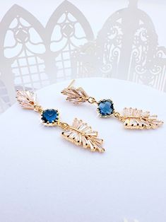 Enhance your look with these stunning Art Deco Leaf Navy Earrings. The navy blue sapphire color adds a touch of elegance to any outfit, making them an excellent accessory for any occasion. Eye-catching Design: The Art Deco design of these earrings is sure to make you stand out from the crowd. Boho Bridal Accessory: Perfect for boho brides, bridesmaids, maid of honor and as a gift for her on her special day. Premium Quality: These earrings are made with high-quality materials that are sure to las Elegant Dangle Crystal Earrings For Gift, Blue Drop Earrings For Bridal Gift, Blue Bridal Drop Earrings As A Gift, Blue Dangle Bridal Earrings For Celebration, Blue Drop Earrings For Bridal Celebration, Blue Dangle Bridal Earrings Gift, Elegant Blue Chandelier Earrings For Celebration, Blue Drop Bridal Earrings For Celebration, Elegant Blue Earrings For Party