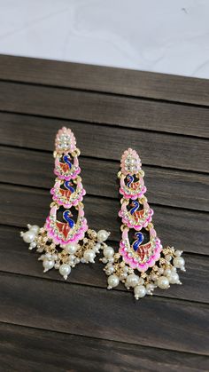 A pair of golden-toned Traditional Floral Hand Painted Yellow Meenakari Jhumka for Women. This Lightweight dome Shaped Meenakari Earrings with Hanging Pearls is very much in high trend gives you a real ethnic as well as antique look. It looks beautiful, is durable & also affordable. This Meenakari Hand Painted Earring is designed for all age groups. Featuring an exquisite design, these meenakari earrings will go well with any Indian outfit. You can match it up with Saree, Lehenga Choli, Salwar S Multicolor Chandbali Jewelry With Peacock Design, Multicolor Chandbali Bridal Earrings In Temple Jewelry Style, Navratri Meenakari Earrings Gift, Peacock Design Earrings For Festivals And Celebrations, Navratri Gift Meenakari Earrings, Temple Style Multicolor Chandbalis For Festivals, Multicolor Chandbali Temple Jewelry Danglers, Multicolor Chandbali Earrings With Cutdana, Multicolor Chandbali Danglers For Diwali