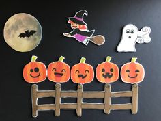 a black table topped with lots of cut out pumpkins next to a wooden fence