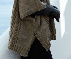 a close up of a person wearing a sweater and holding a handbag in their other hand