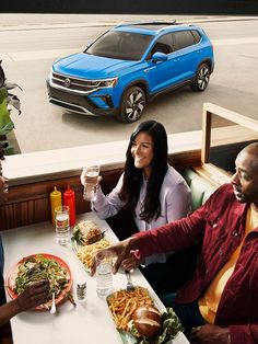 three people sitting at a table with plates of food and drinks in front of them