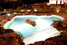 an outdoor swimming pool surrounded by rocks at night